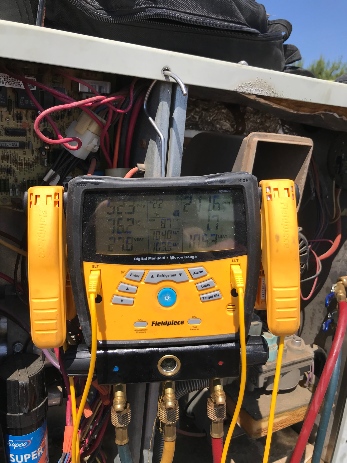 Digital manifold gauge reading refrigerant pressures on a residential AC unit